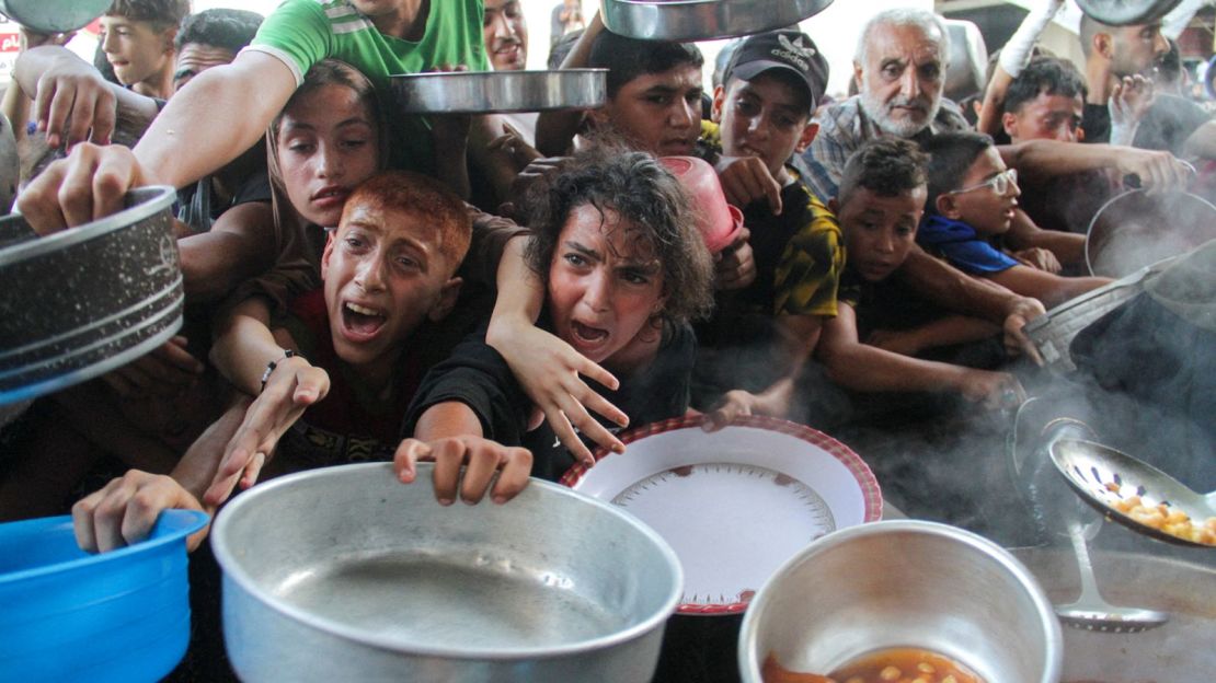 Palestinians receive food cooked at a charity kitchen in northern Gaza on September 11, 2024.